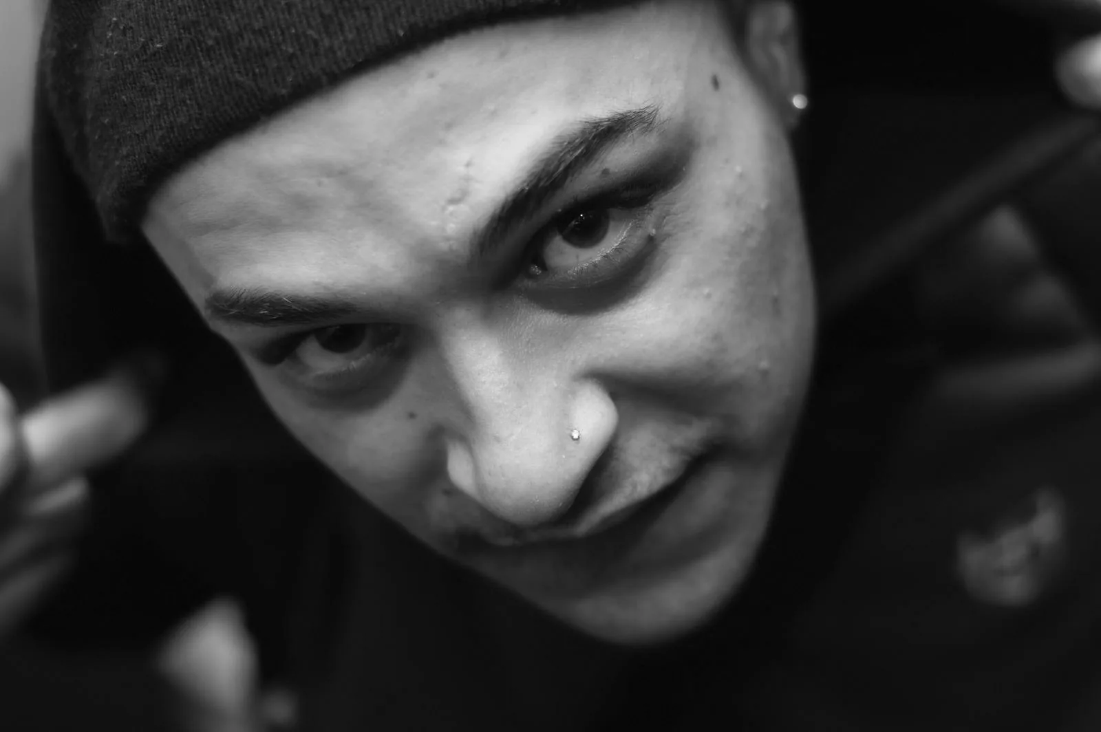 Primer plano en blanco y negro de un chico con gorro mirando a cámara